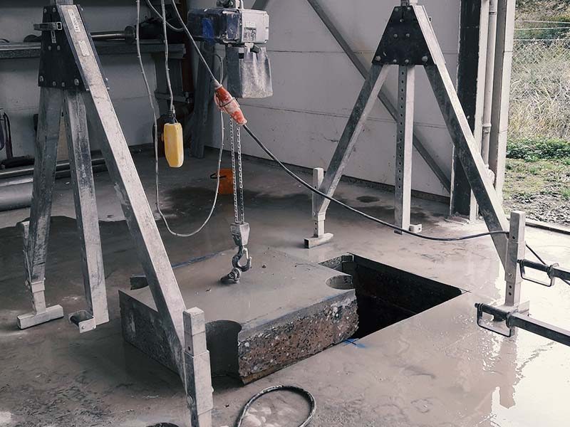 Ausgesägter Betonblock wird mit Hebezeug aus einer Bodenöffnung gehoben