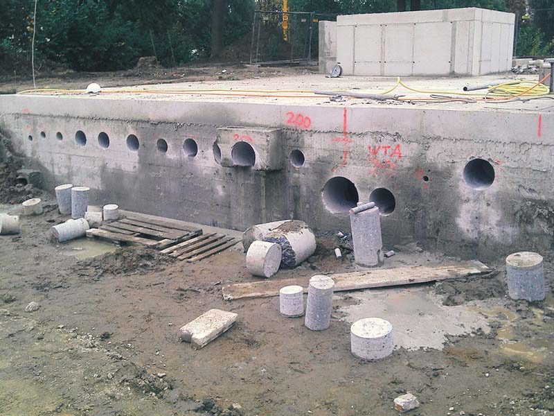 Reihe von Kernbohrungen in einer Betonstützwand, davor liegen die herausgezogenen Bohrkerne